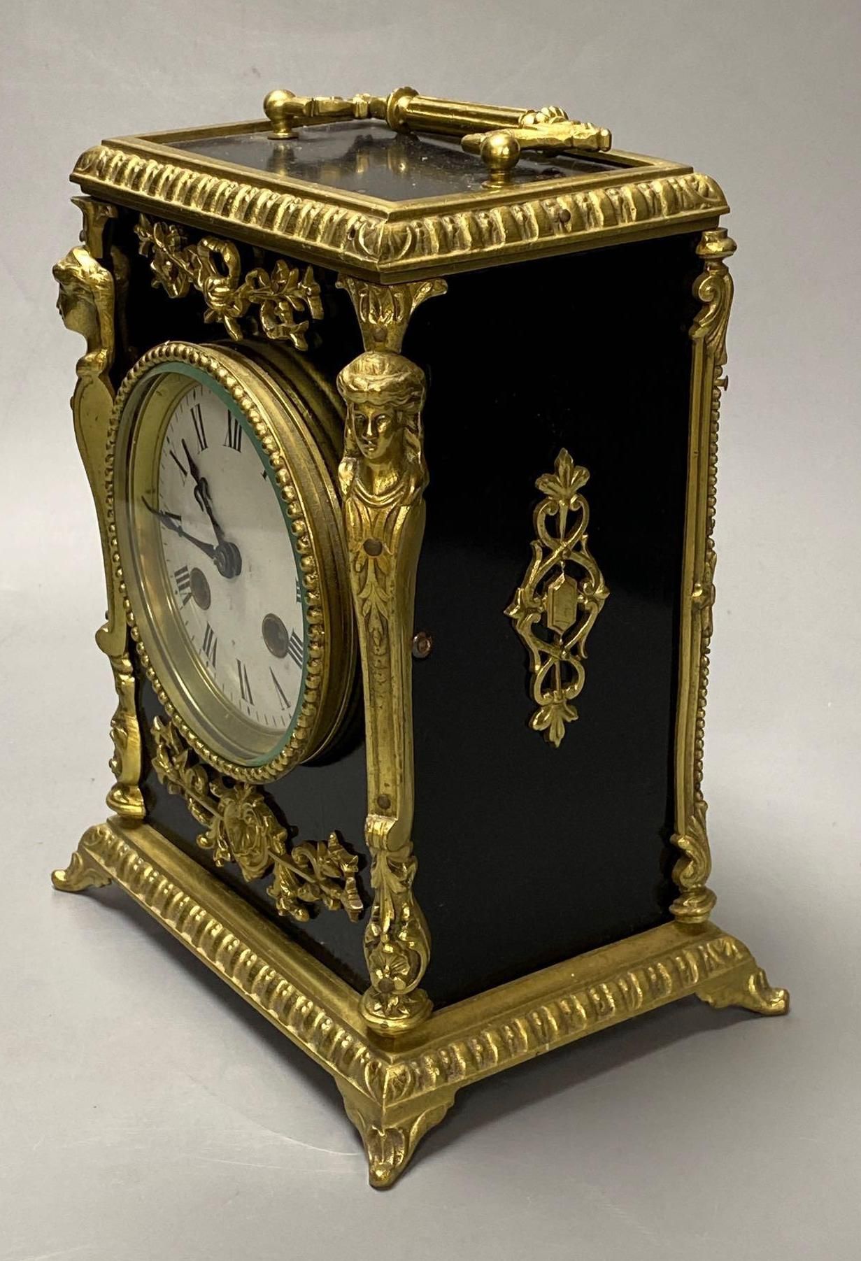 A French ebonised mantel clock with cast brass mounts, 9cm convex enamel dial, bell striking movement, height 27cm incl. handle